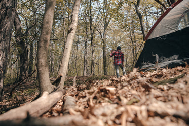 camper standing beside tent with axe