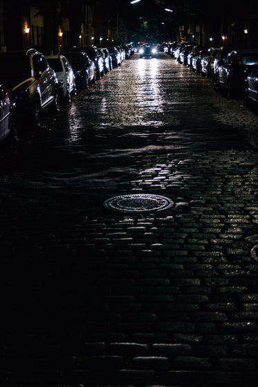 car drives down cobblestone road at night