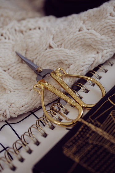 carved gold and silver scissors lay on a white fabric