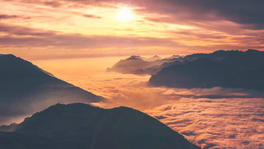 cascading clouds surrounding hilltops at sunset