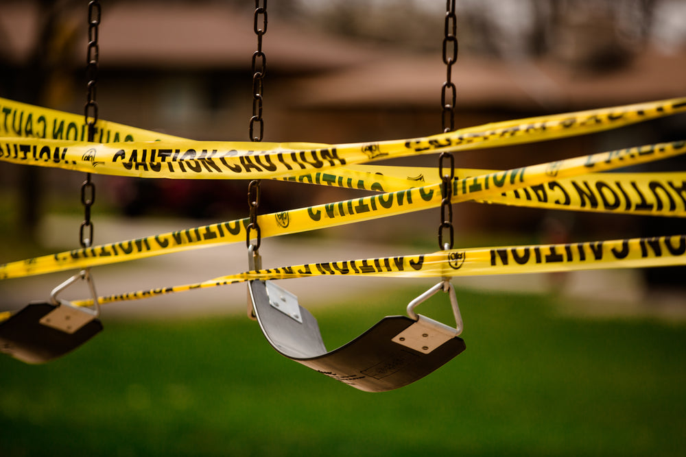 caution tape wrapped around empty swings