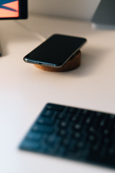 cell phone and wireless charger on white desk