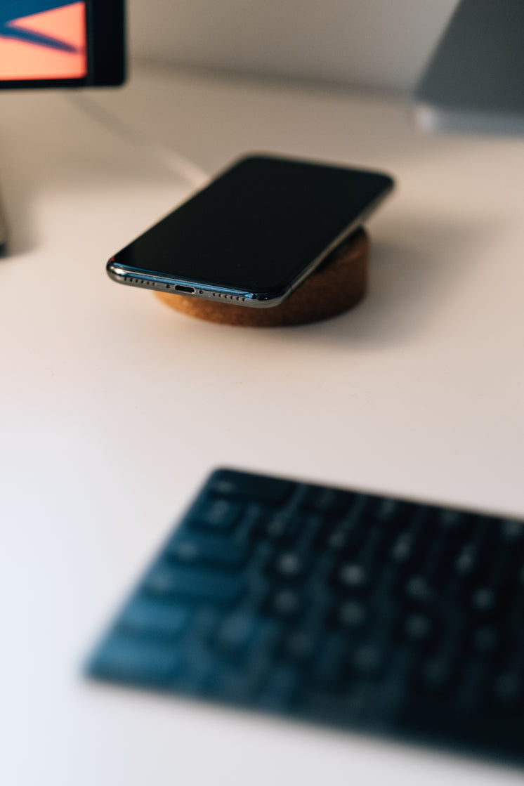 Cell Phone And Wireless Charger On White Desk