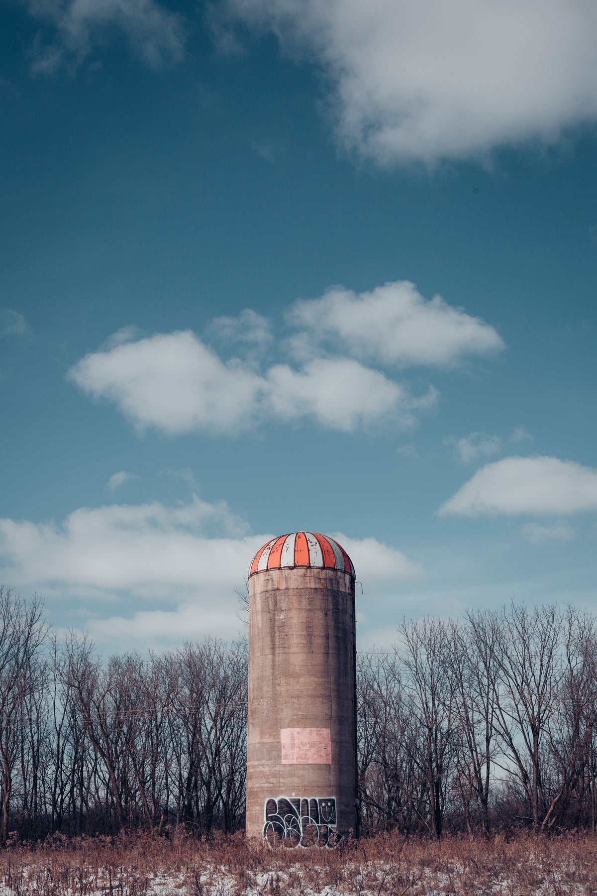 cement farm silo with red and white striped roof