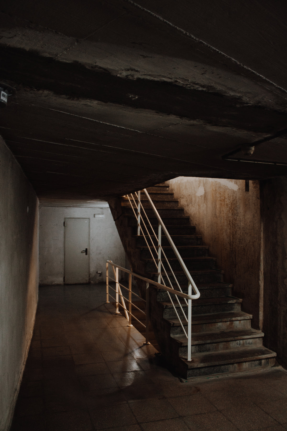 cement staircase with white railing in dark building