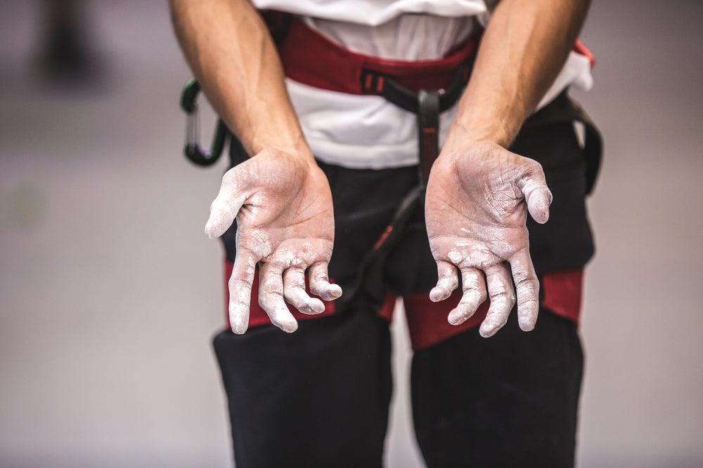 chalk covered hands in rock climbing gear