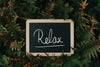 chalkboard sits in green and brown ferns and reads relax