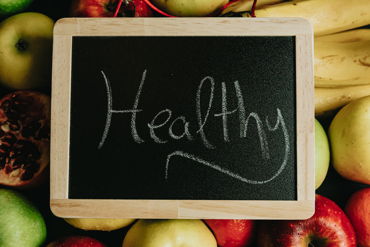 黑板上用草书写着“健康”，放在水果上