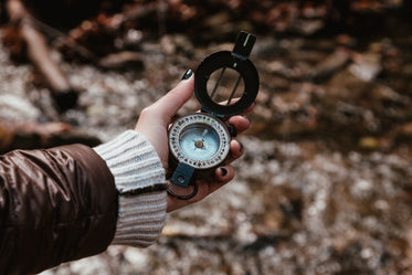 checking a compass on a hike through the woods