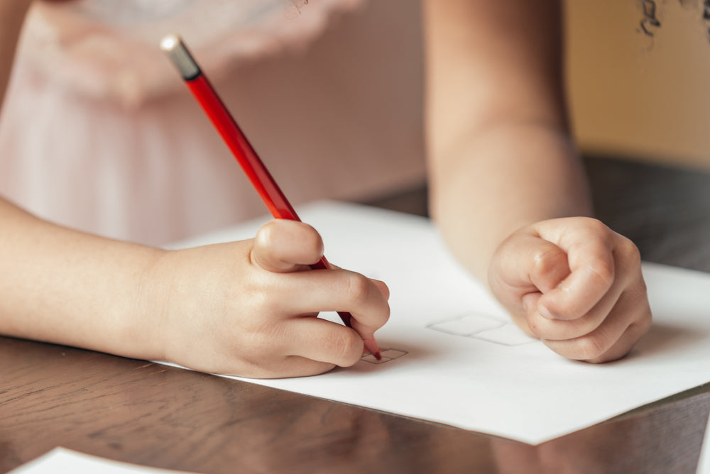 child drawing with red pencil crayon