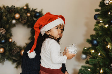 child helps decorate christmas tree