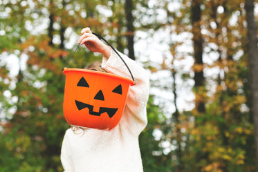 child holding jack-o-lantern pail