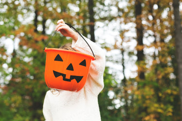 child holding jack-o-lantern pail