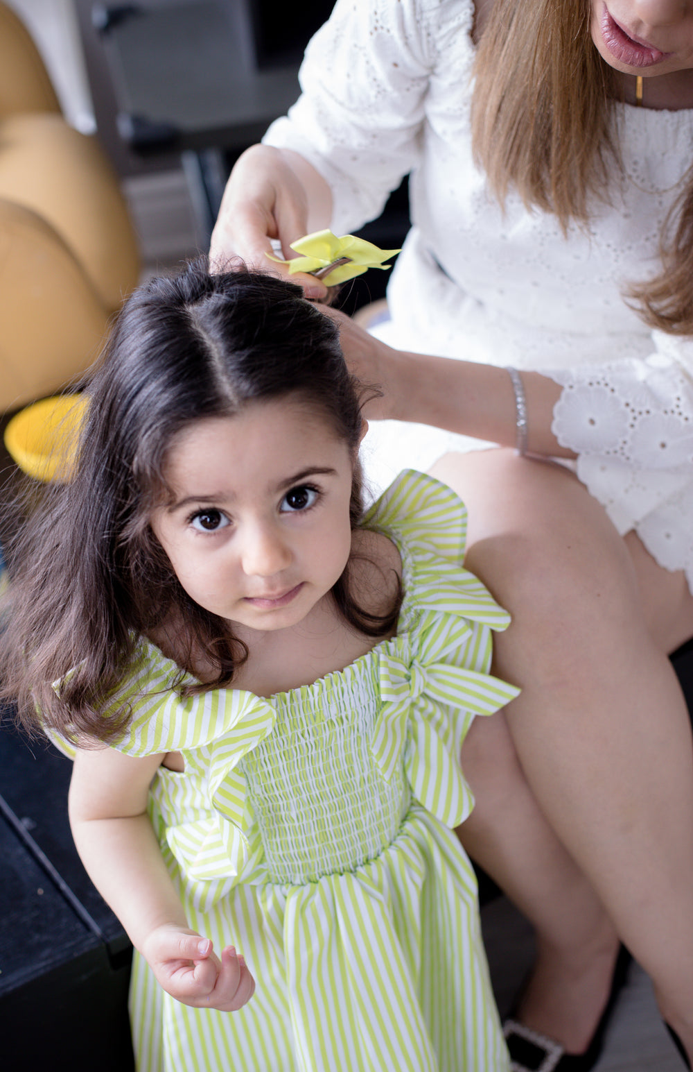 child in a green and white dress looks up at the camera