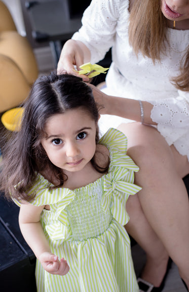 child in a green and white dress looks up at the camera