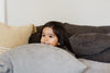 child peeks through pillows