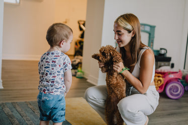 child says hello to a puppy held up by an adult