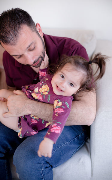 child smiles at camera while being cradled in arms