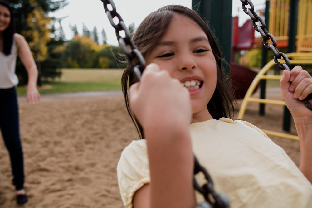 child smiles big on swing set