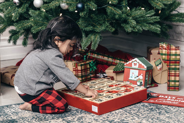 criança com o calendário do advento perto da árvore de natal