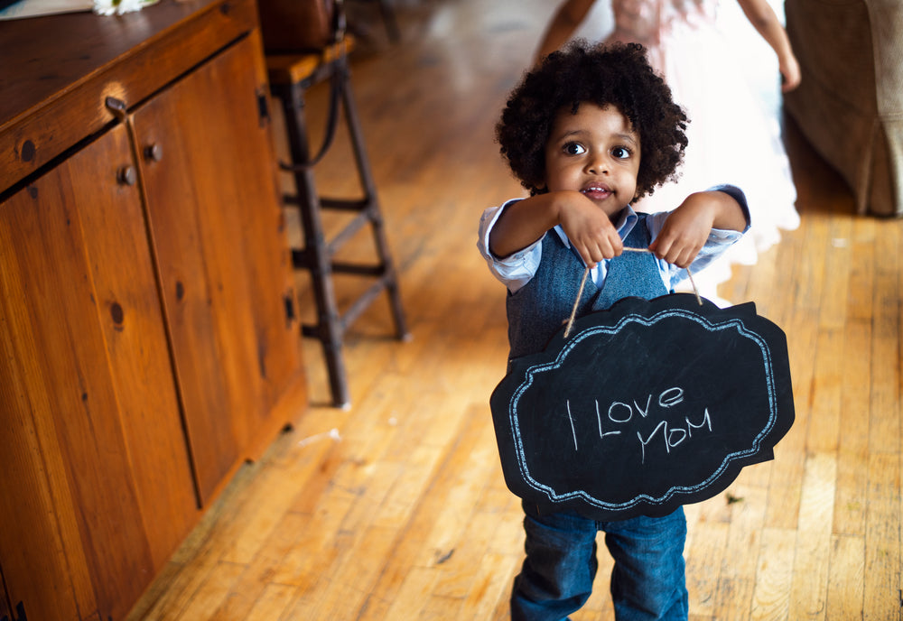 child with i love mom sign