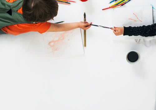 children sharing paint brush