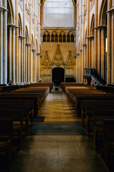 church pews line an aisle with a doorway at the end