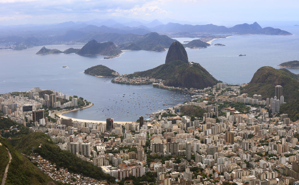 city from the distance sits in green hills by water