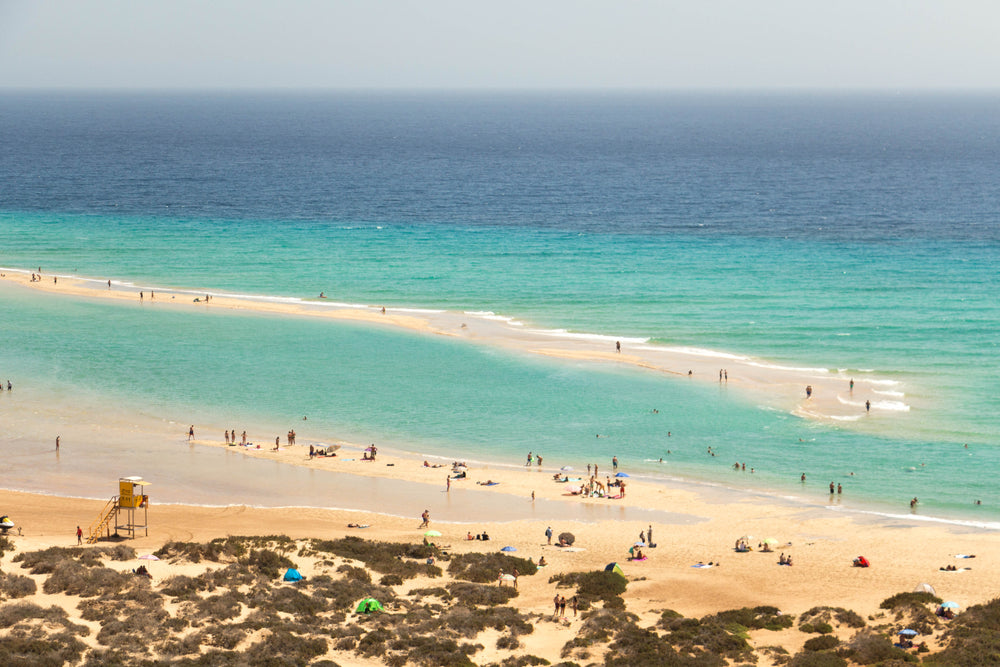 clear blue sea surrounds a small bank of sand