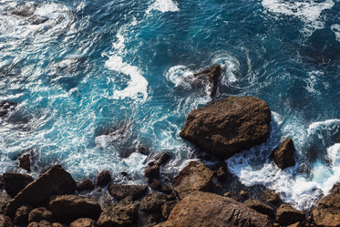 clear blue water crashes against rocks