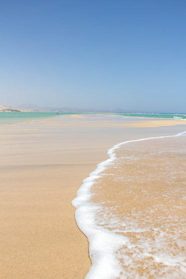 clear blue water crawls over the white sandy beach