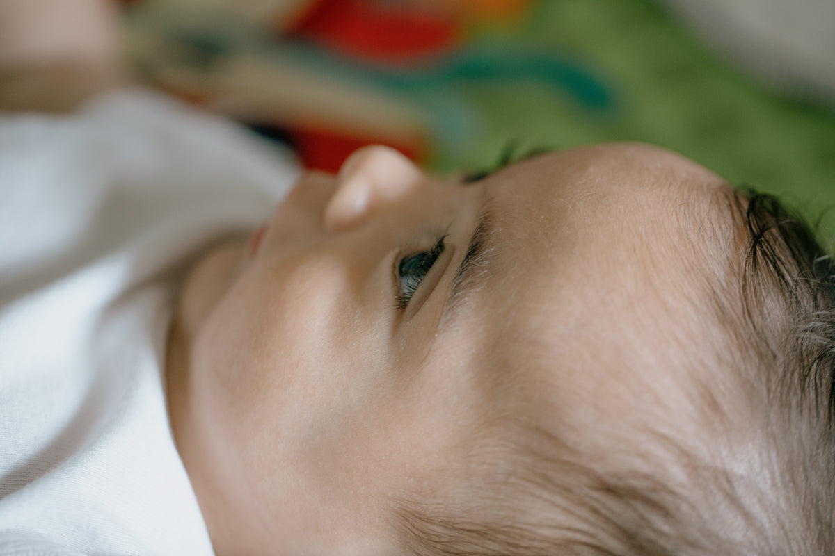 在彩色垫子上一个婴儿的脸的侧面特写