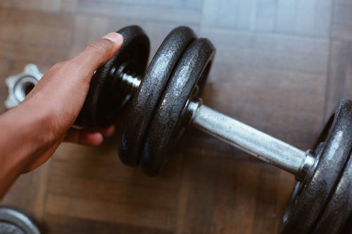 close up of a hand adding weight to a dumbbell