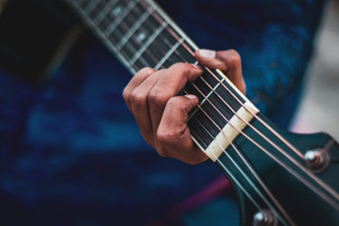 close up of a hand holding the neck of a guitar