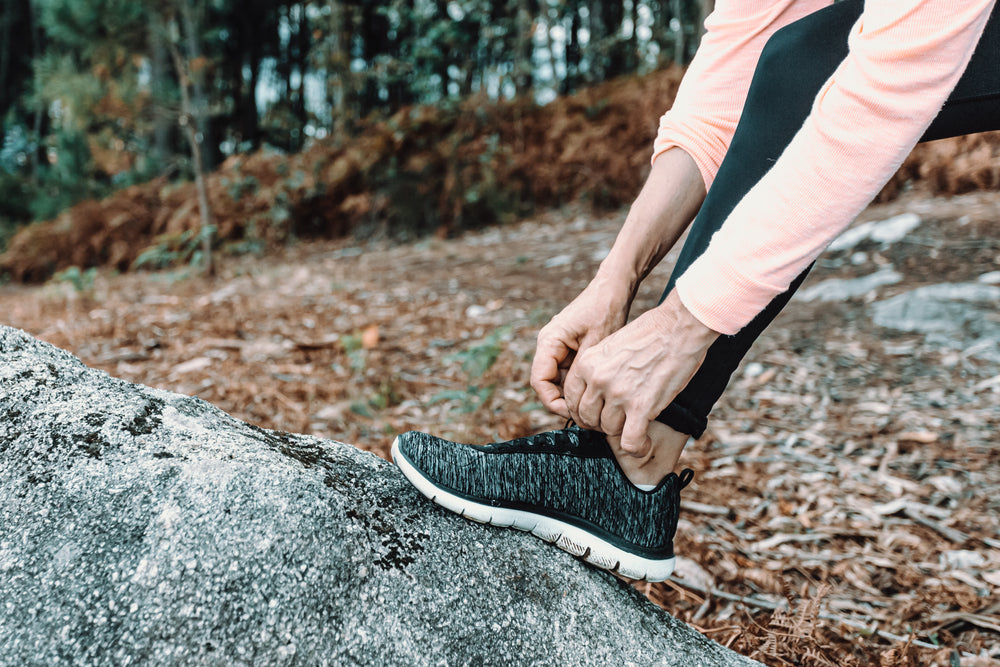 close up of a hiker adjusting there shoes on a big rick