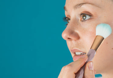 close up of a makeup brush held to a persons cheekbone