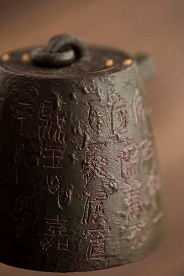 close up of a metal teapot with text carved into it