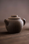 close up of a mini round teapot with letters carved