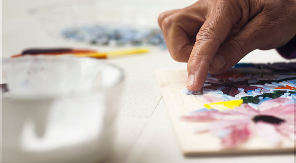 close up of a persons hand adding glass to a mosaic