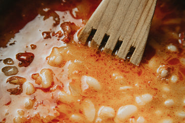 close up of a red sauce and a wooden spoon