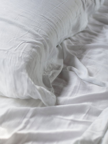 close up of a white sheets and pillow on a cozy bed