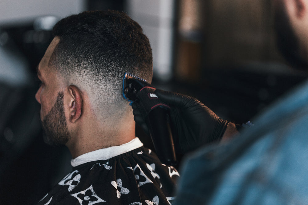 Close-up of a barber using clippers while giving a client a fade