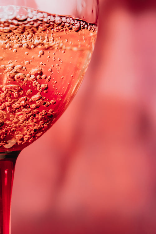 close up of bubbles in a pink glass