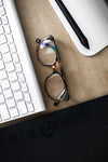 close up of eye glasses on a computer desk