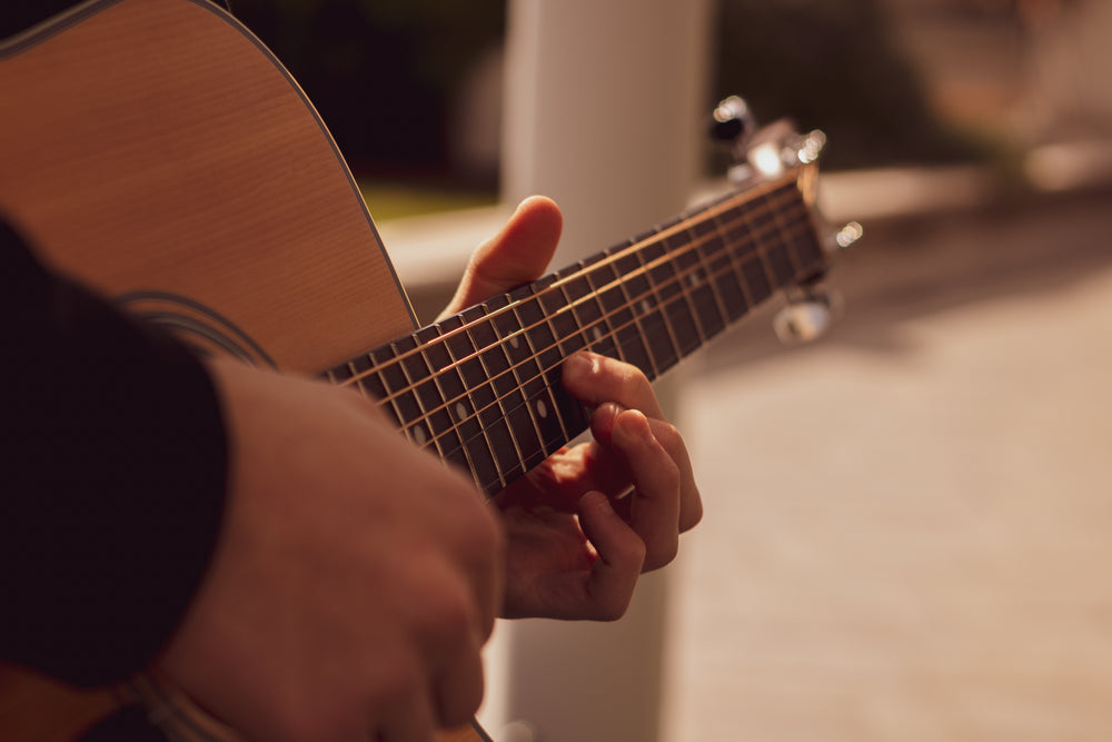 close up of hands playing an acoustic guitar