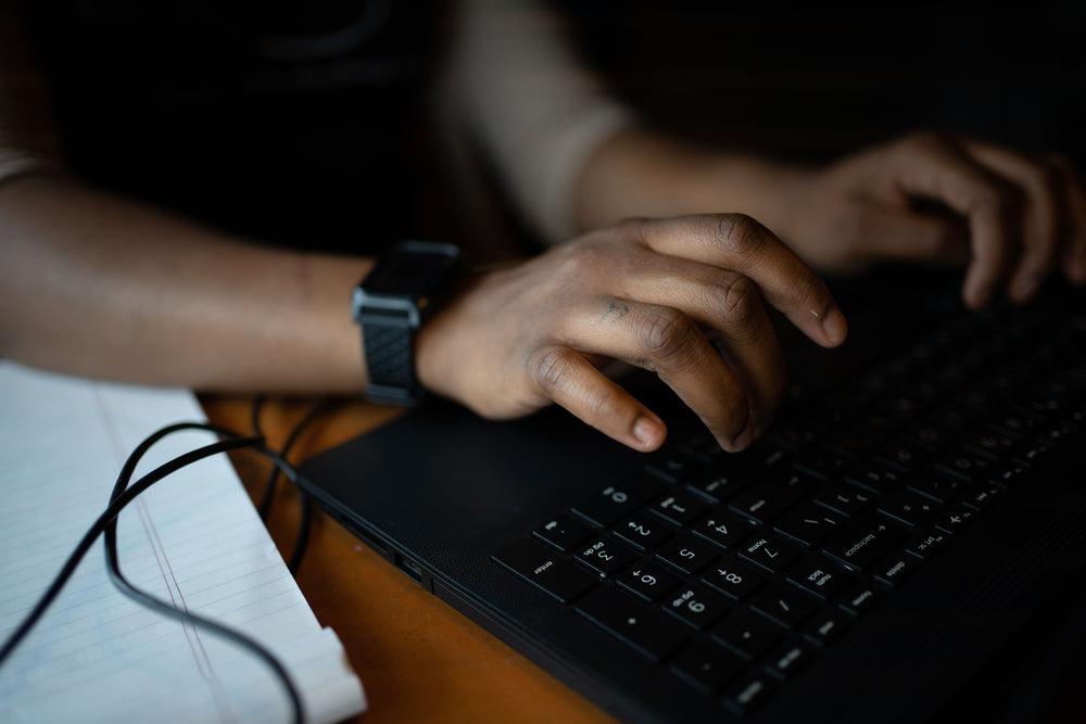 close up of hands typing on a black laptop