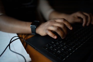 close up of hands typing on a black laptop