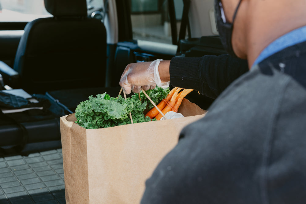 close up of man placing groceries in back of car