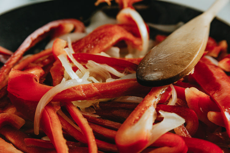 Close Up Of White Onions And Red Peppers Cooking In A Pan