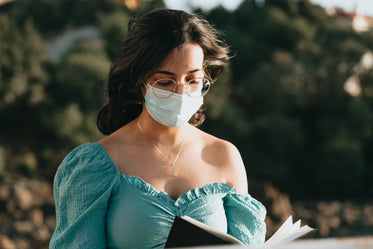 close up of woman reading in a blue face mask